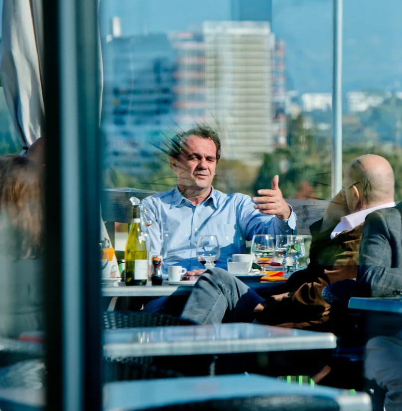 Discussion entre professionnels à la terrasse d'un restaurant panoramique, avec vue sur la ville