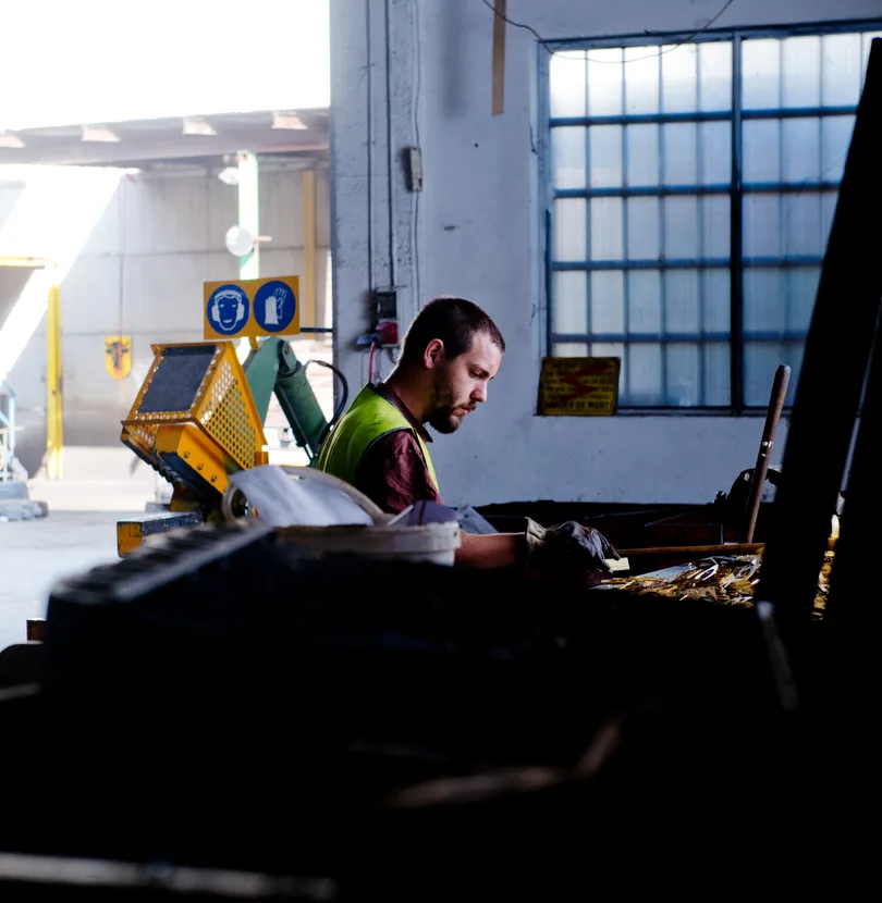 Ouvrier en gilet de sécurité à son poste dans un atelier industriel